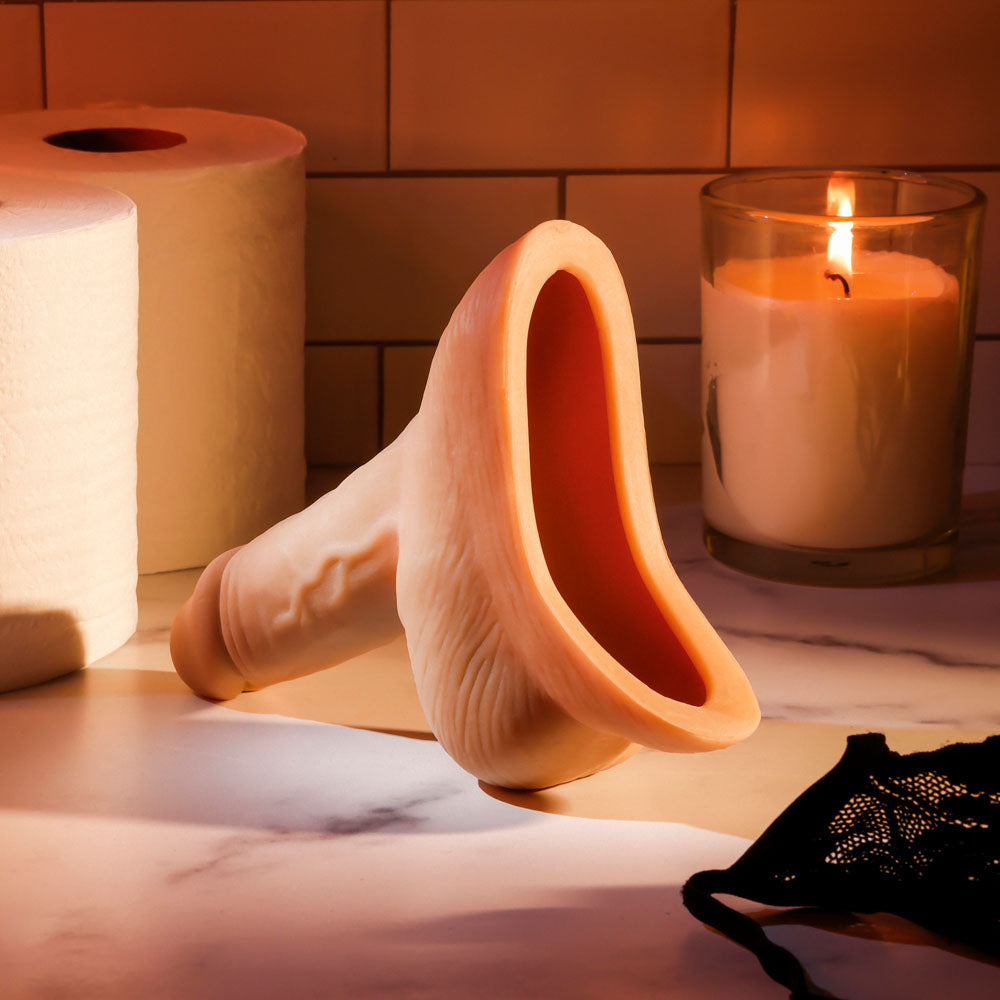Gender X STAND TO PEE - Light -  Realistic Stand-To-Pee Funnel on a marble surface with candle and toiletries.
