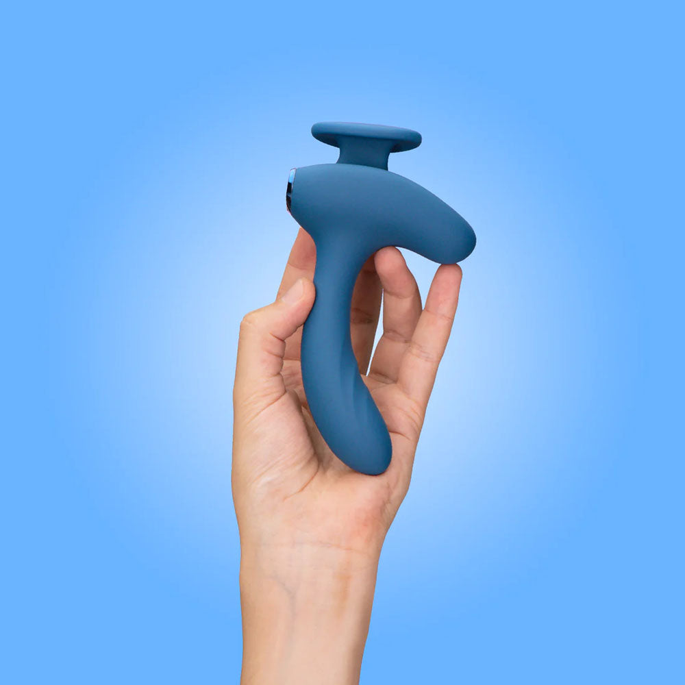JimmyJane Solis Kyrios - USB Rechargeable Prostate Massager with Remote in a hand against a blue background.