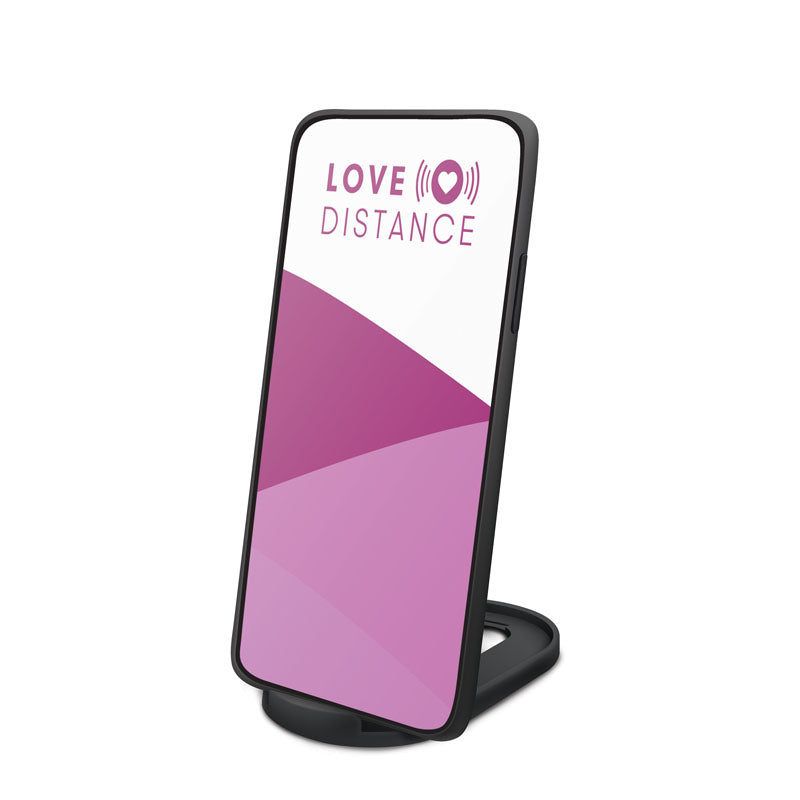 Love Distance REACH - Rose Rechargeable Strap-On Stimulator with App Control displayed on a smartphone stand.
