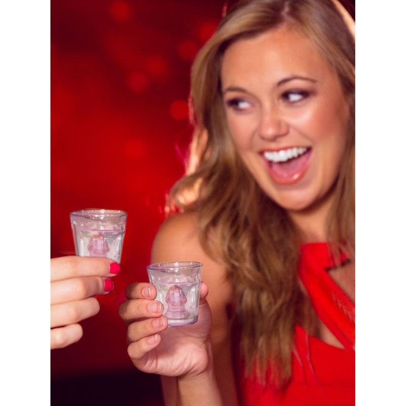 Two friends enjoying fun penis shot glasses at a party, celebrating with laughter and joy.