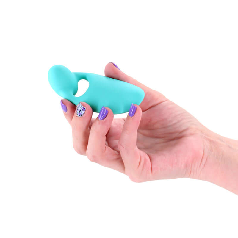 Person holding the INYA Tease teal USB rechargeable finger stimulator in a hand with purple nail polish.