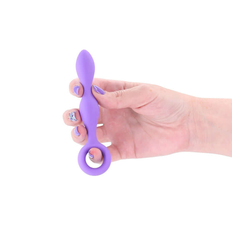 Slim anal plug for beginners held in hand, made of purple plush silicone for comfort and control.