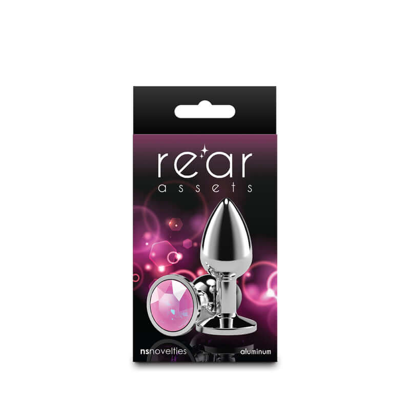 Small metal butt plug with pink gem nestled in a vibrant packaging, showcasing its chrome-plated aluminum design.