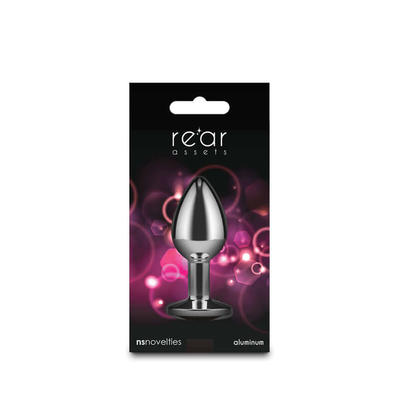 Small metal butt plug with pink gem displayed in packaging, showcasing chrome-plated aluminum design and sleek shape.