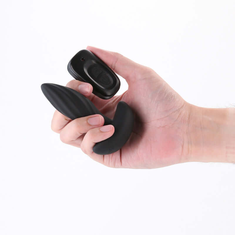 Hand holding Renegade Flash rechargeable vibrating butt plug and remote control.