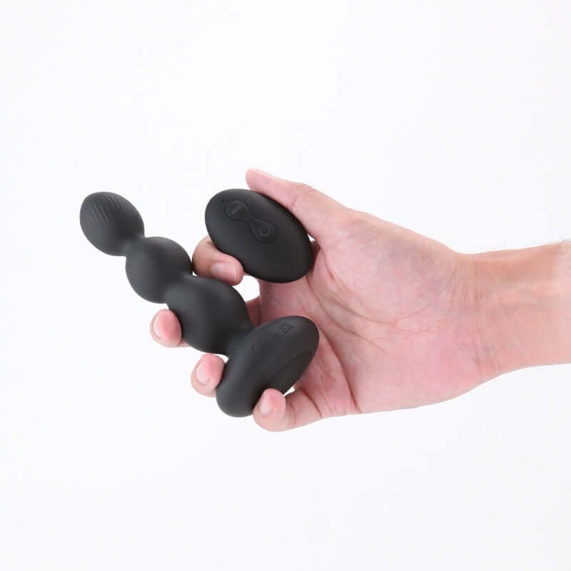 Hand holding Renegade Valor 13.7 cm USB rechargeable vibrating anal beads with wireless remote.