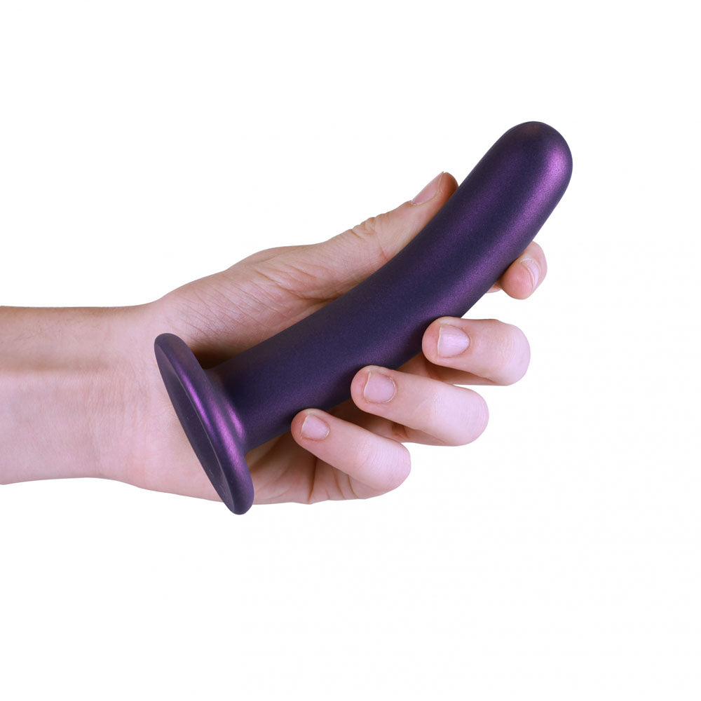 Smooth silicone g-spot dildo in hand showcasing strong suction cup and metallic finish.