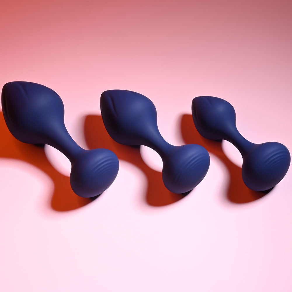 Playboy Pleasure TAIL TRAINER -  Butt Plugs - Set of 3 Sizes in deep blue silicone arranged on a pink background.