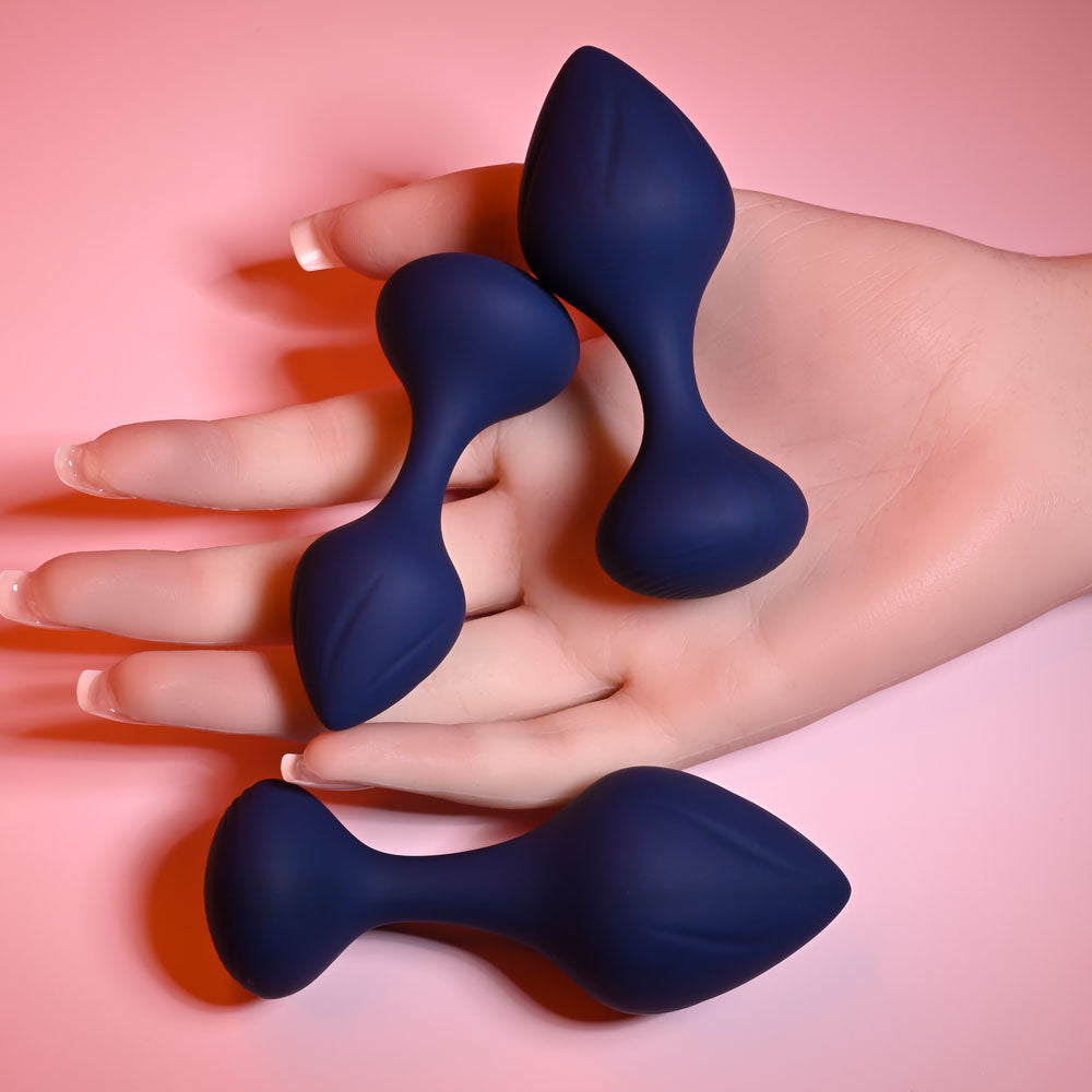 Playboy Pleasure TAIL TRAINER -  Butt Plugs - Set of 3 Sizes held in a hand against a pink background.