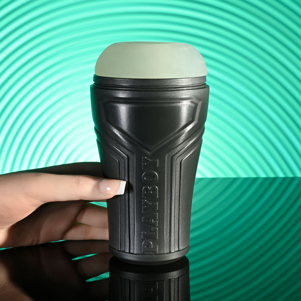 Playboy Pleasure THE URGE SMALL - Clear Small Stroker held in hand, showcasing its sleek design and textured canister.