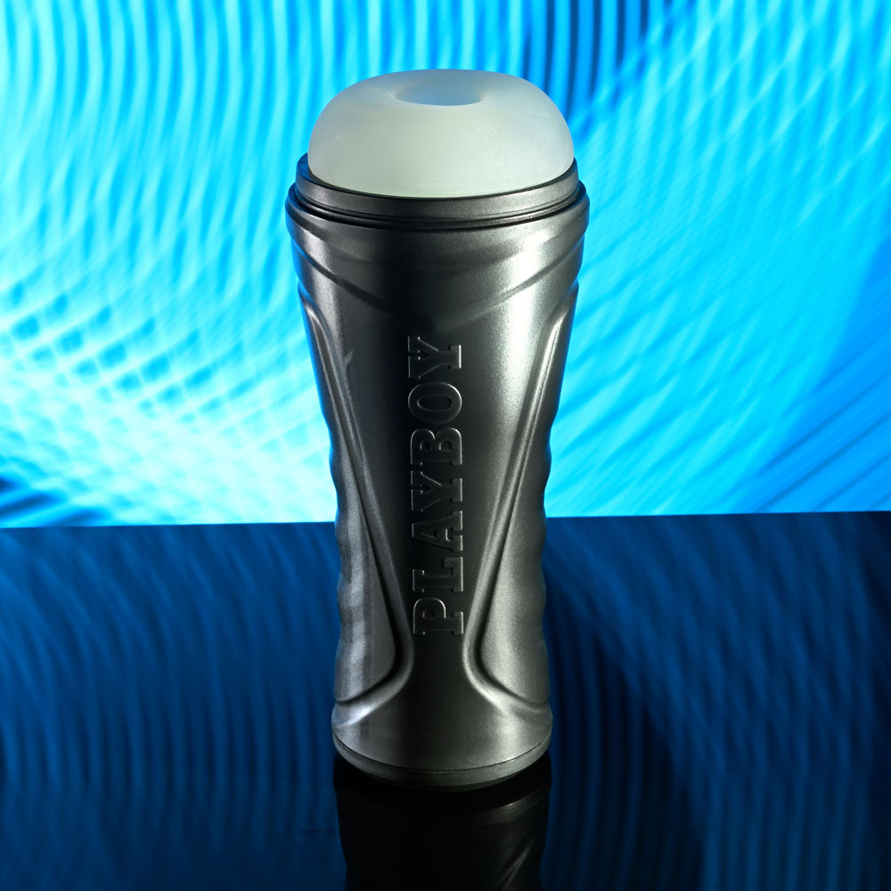 Playboy Pleasure THE URGE MEDIUM - Clear Stroker with textured canister on reflective surface.