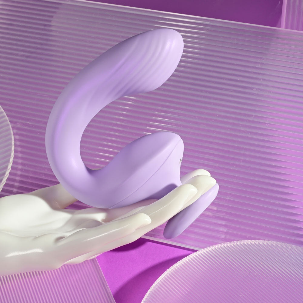 Playboy Pleasure REV ME UP -  USB Rechargeable Dual Motor Curved Vibrator held in a hand with a modern background.