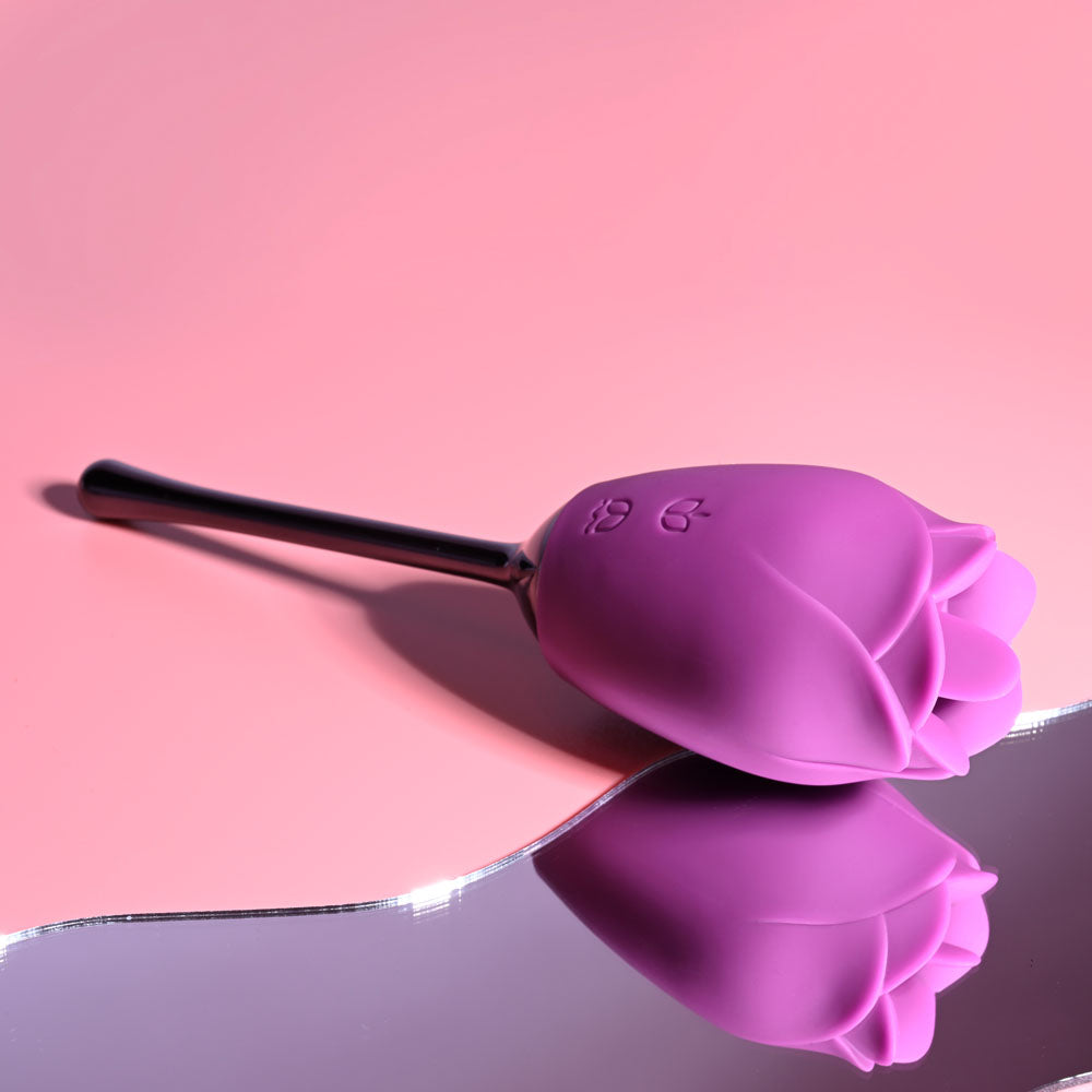 Playboy Pleasure PETAL -  USB Rechargeable Flicking Stimulator on a reflective surface against a pink background.