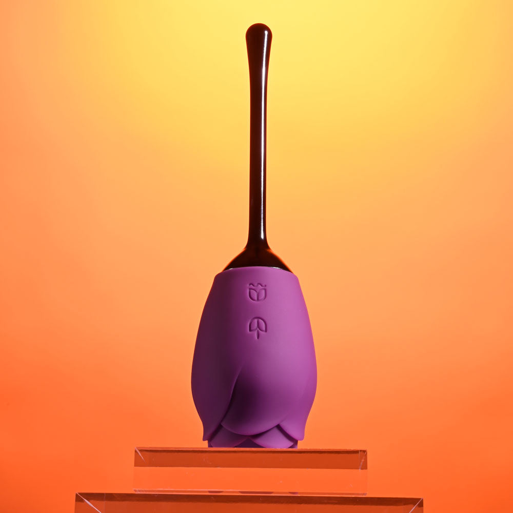 Playboy Pleasure PETAL - USB Rechargeable Flicking Stimulator in vibrant purple against a warm orange background.