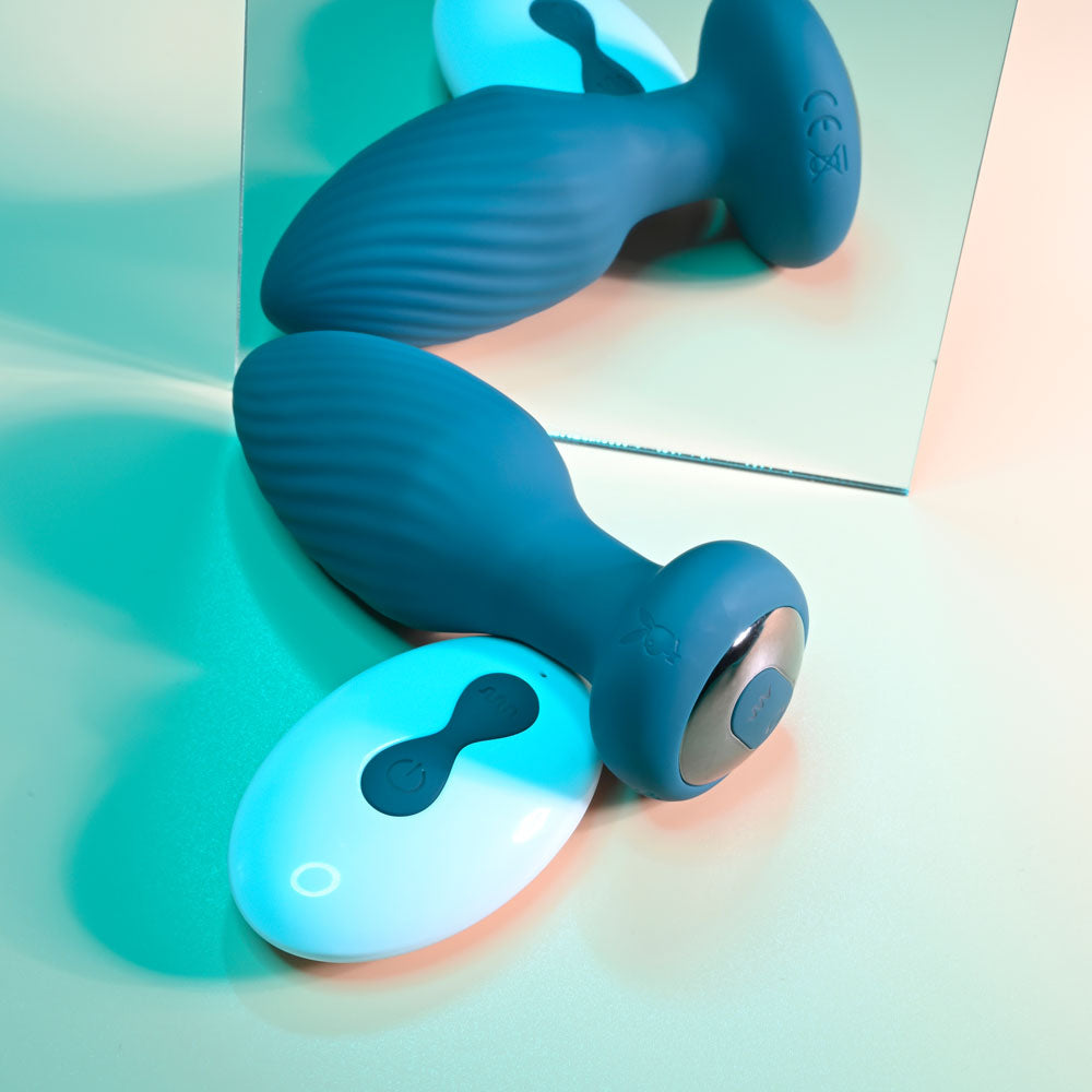 Playboy Pleasure SPINNING TAIL TEASER -  9.7 cm USB Rechargeable Vibrating & Rotating Butt Plug with Wireless Remote on a reflective surface.