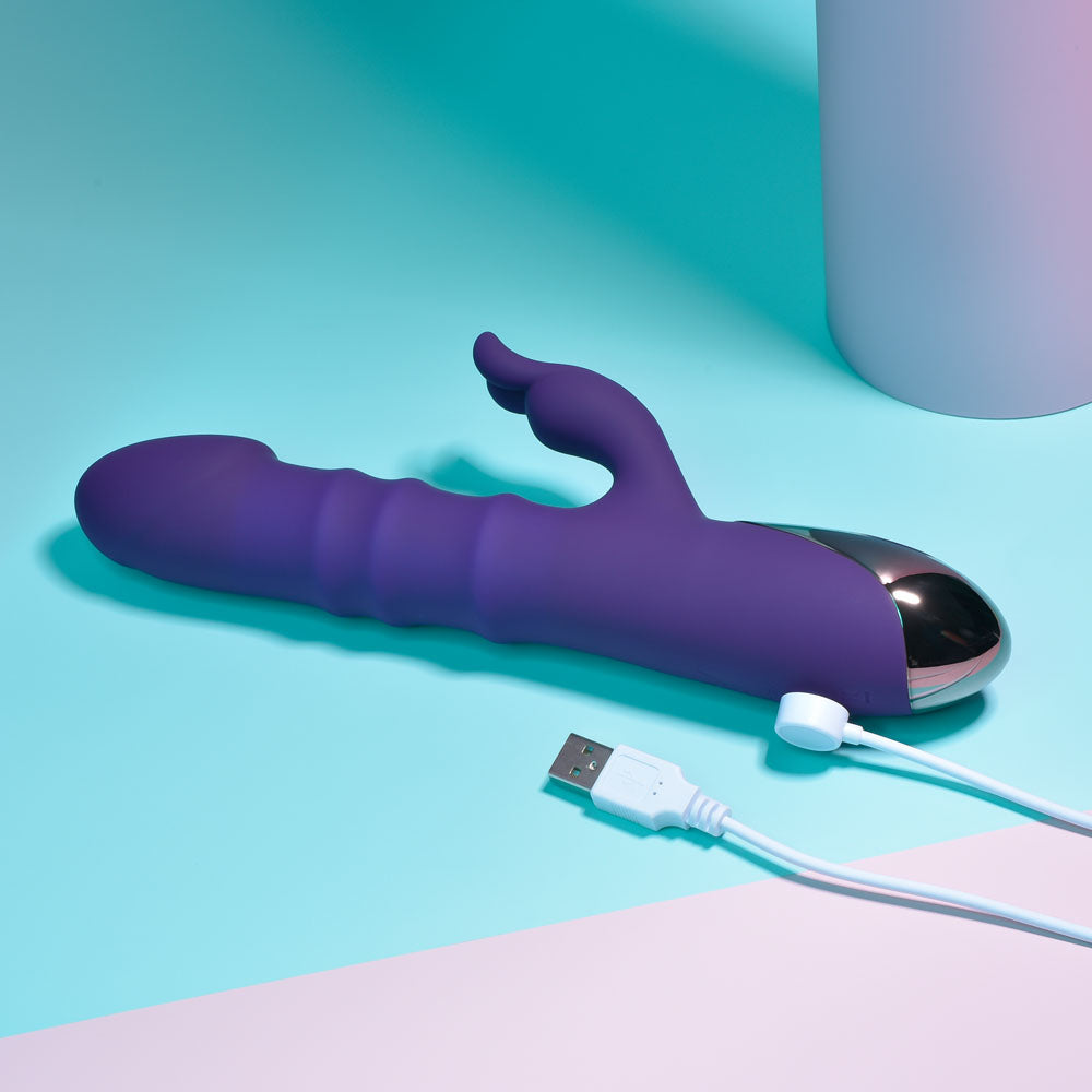 Playboy Pleasure HOP TO IT - 23.5 cm USB Rechargeable Rabbit Vibrator on a teal surface with USB charging cable.