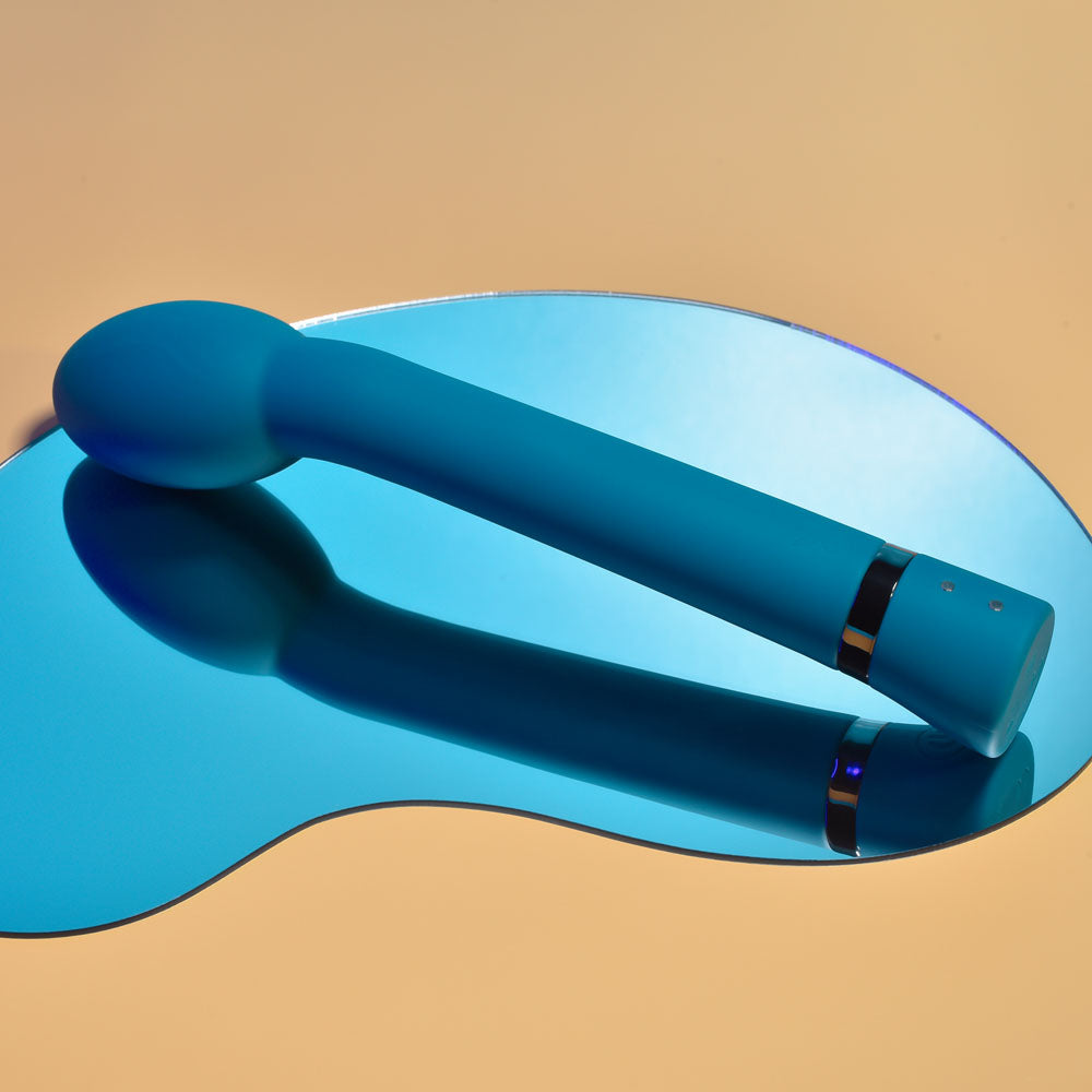 Playboy Pleasure ON THE SPOT G-Spot vibrator reflecting on a blue mirror surface.