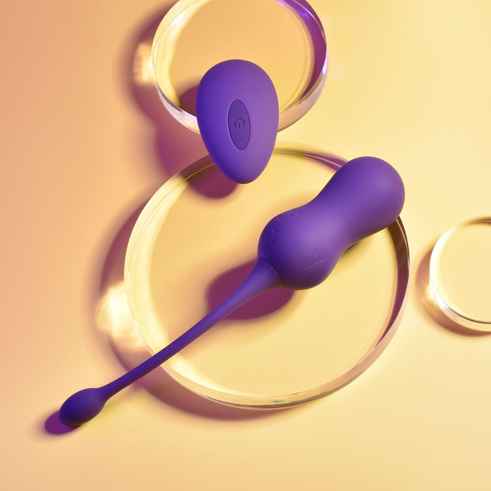 Playboy Pleasure DOUBLE TIME - USB Rechargeable Vibrating Kegel Balls in purple on a soft surface.