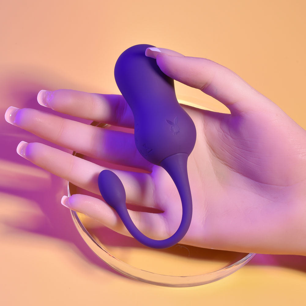 Playboy Pleasure DOUBLE TIME - USB Rechargeable Vibrating Kegel Balls in a hand on a vibrant background.