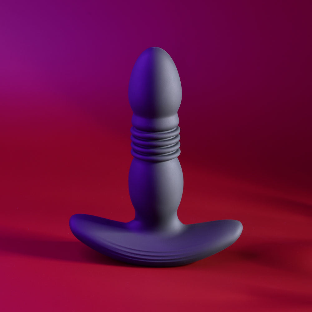 Playboy Pleasure TRUST THE THRUST -  13.7 cm USB Rechargeable Thrusting Butt Plug with Wireless Remote on red background.