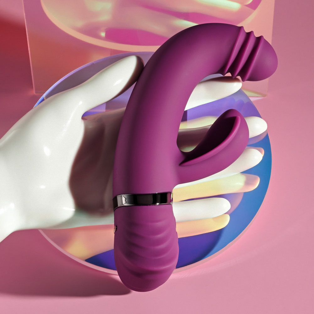Playboy Pleasure TAP THAT -  16.5 cm USB Rechargebale Rabbit Vibrator in a hand with colorful background.