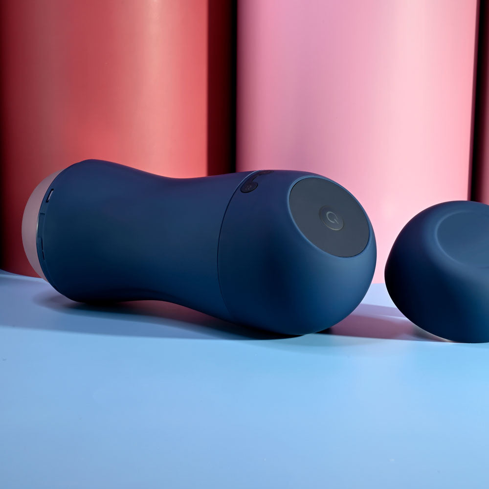 Playboy Pleasure GUSTO - USB Rechargeable Vibrating & Sucking Masturbator on a blue surface with colorful background.