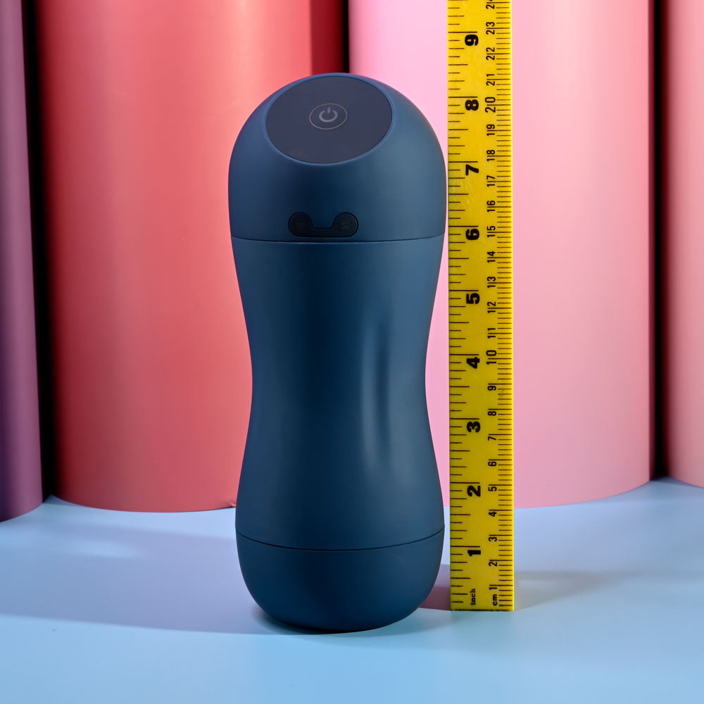 Playboy Pleasure GUSTO - USB Rechargeable Vibrating & Sucking Masturbator next to a ruler for size comparison on colored background.