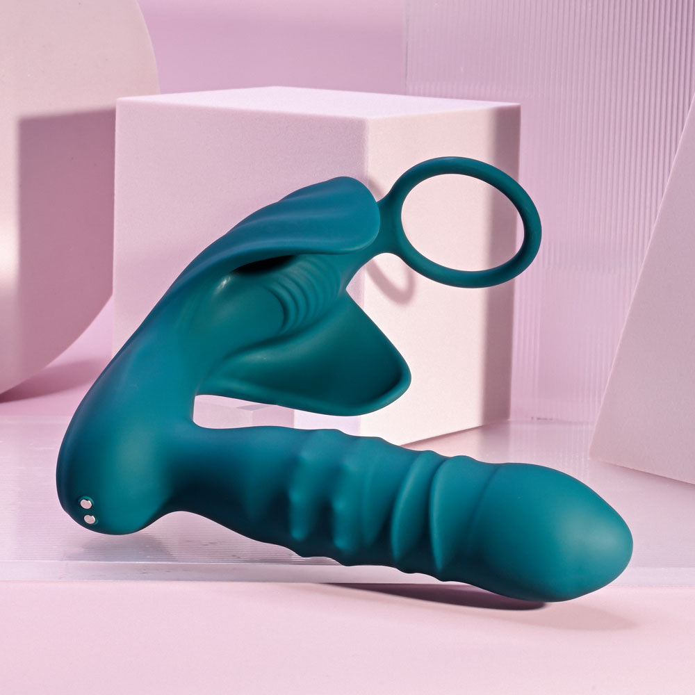 Playboy Pleasure BRING IT ON - Teal USB Rechargeable Thrusting Anal Plug with Cock Ring on a pastel background.