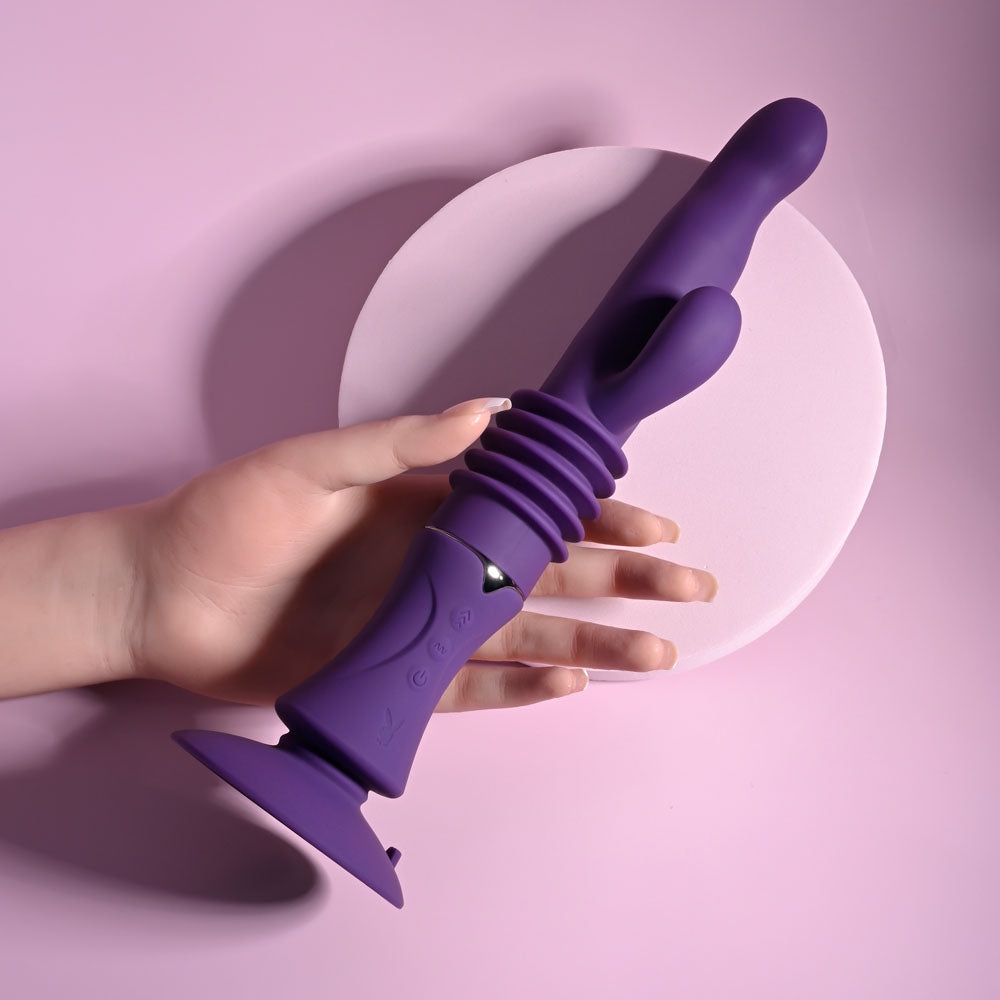 Playboy Pleasure HOPPY ENDING - 29.2 cm USB Rechargeable Thrusting Rabbit Vibrator in hand against a pink background.