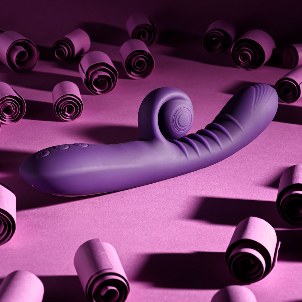 Playboy CURLICUE - 23.5 cm USB Rechargeable Rabbit Vibrator surrounded by pink rolled paper.