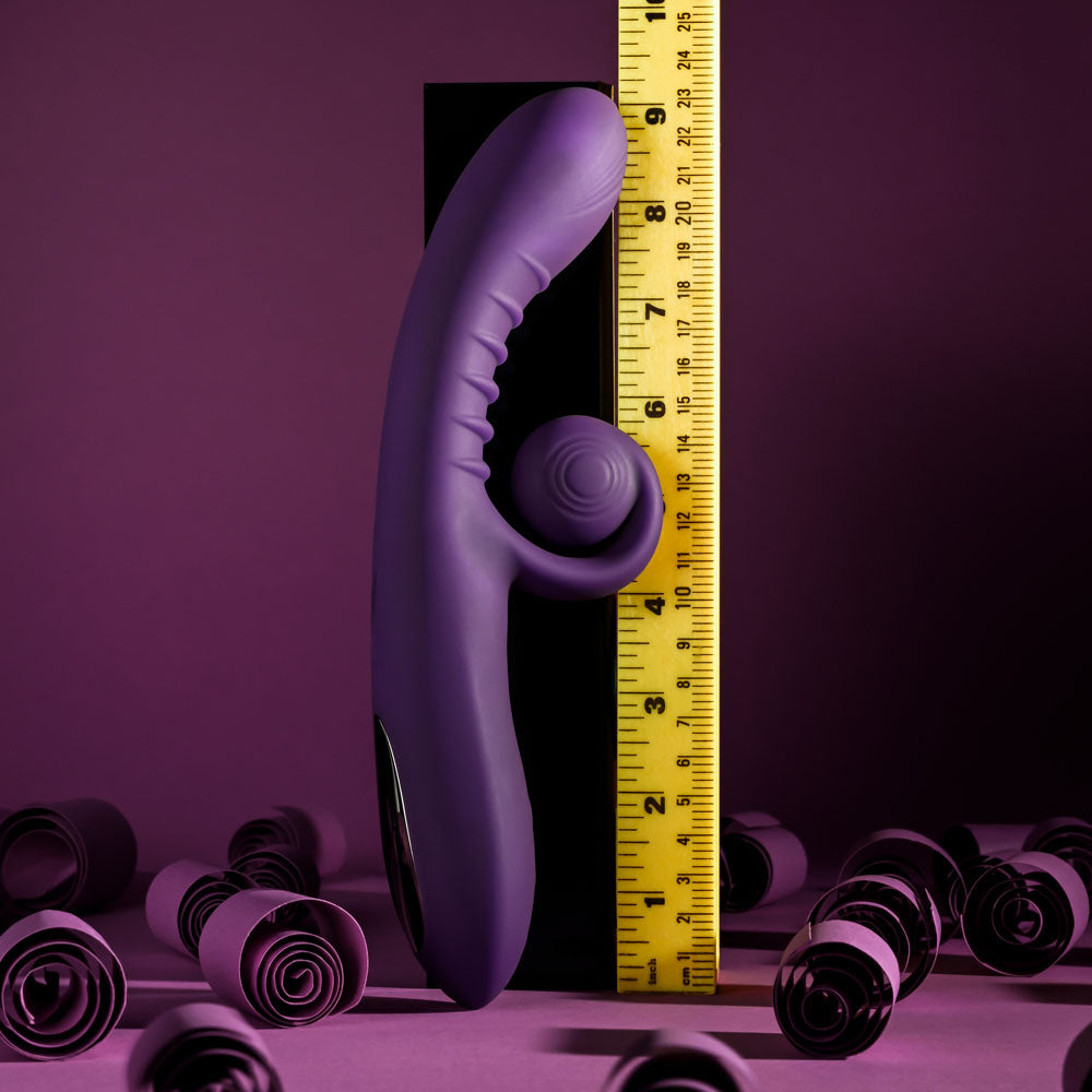 Playboy CURLICUE - 23.5 cm USB Rechargeable Rabbit Vibrator with measurement tape against a purple background.