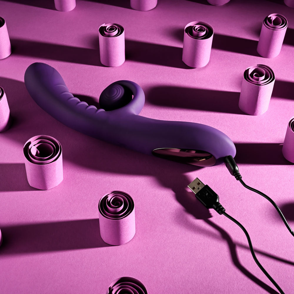 Playboy CURLICUE - 23.5 cm USB Rechargeable Rabbit Vibrator on a pink background with decorative rolls.