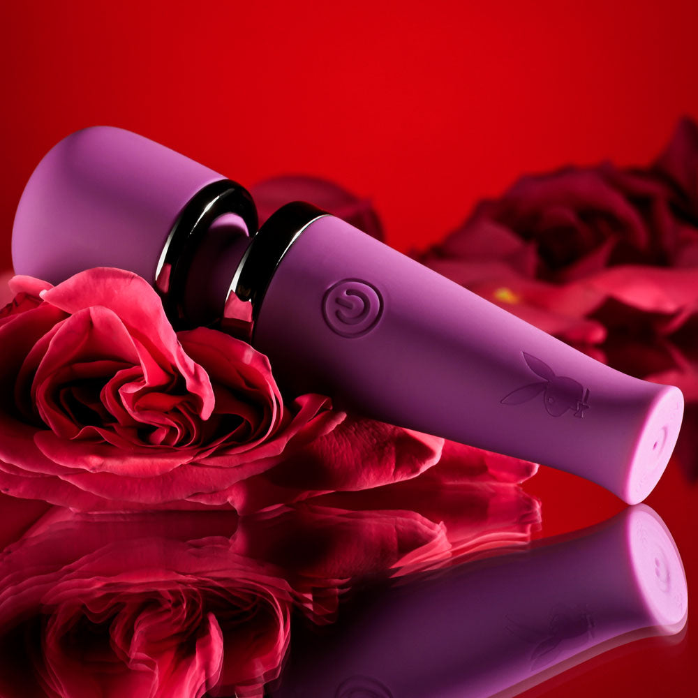 Playboy Pleasure MIC DROP -  11.4 cm USB Rechargeable Vibrating Mini Massage Wand with rose petals on red background.