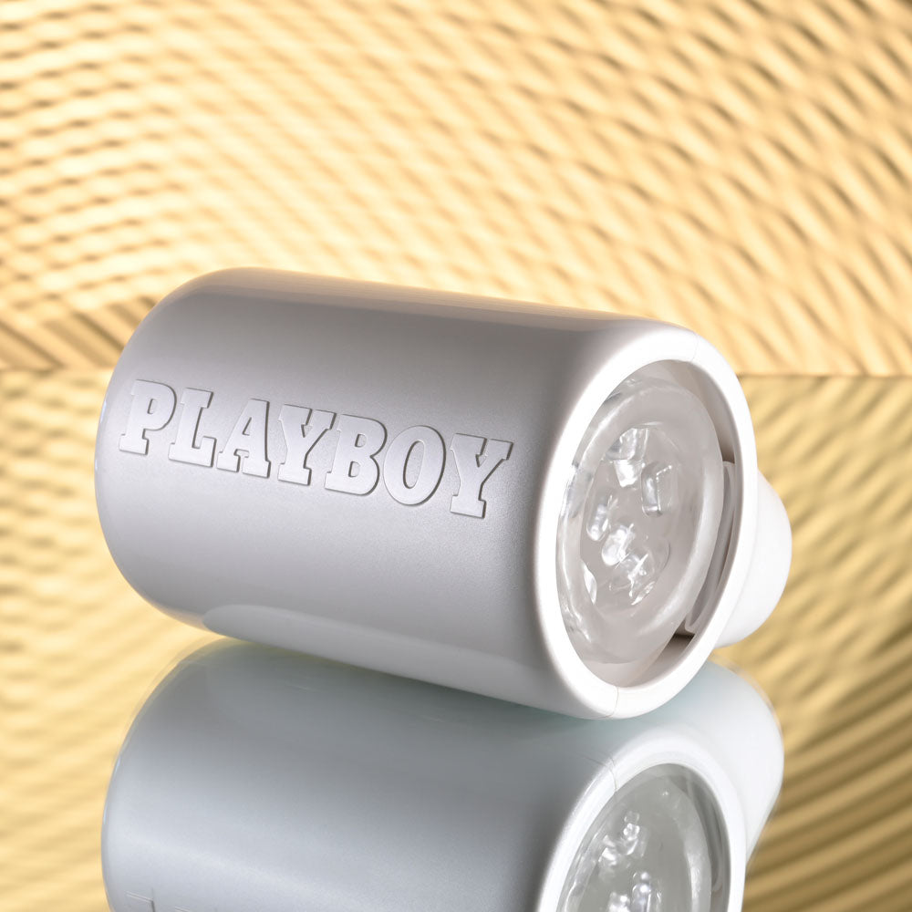 Playboy Pleasure SPIN DOCTOR USB rechargeable vibrating stroker with a sleek design on a reflective surface.
