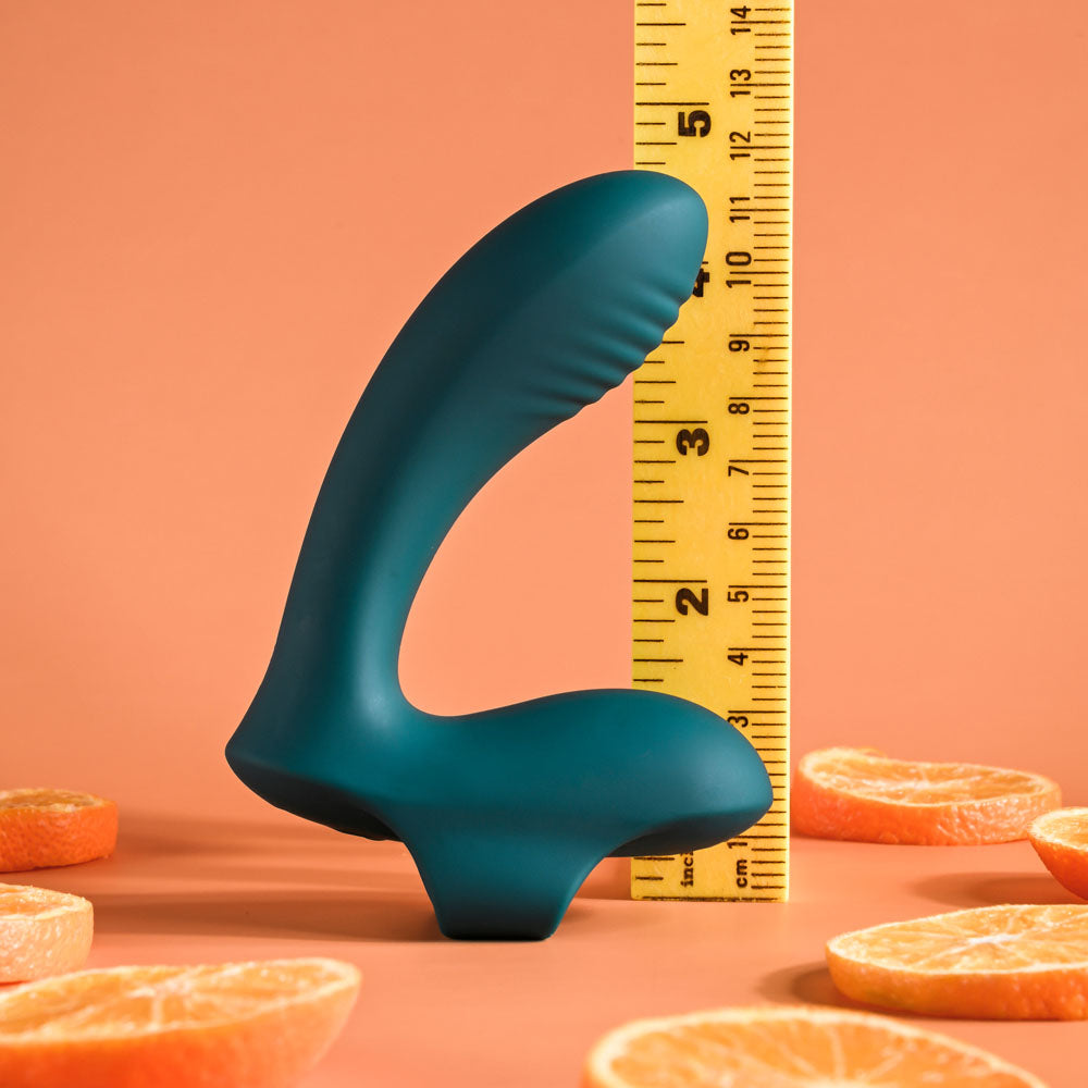 Playboy Pleasure WRAPPED AROUND YOUR FINGER -  USB Rechargeable Finger Stimulator next to a ruler and orange slices.
