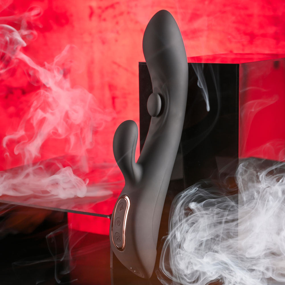 Playboy Pleasure THATS THE SPOT -  23.3 cm USB Rechargeable Rabbit Vibrator with G-Spot Tapper on a smoky background.