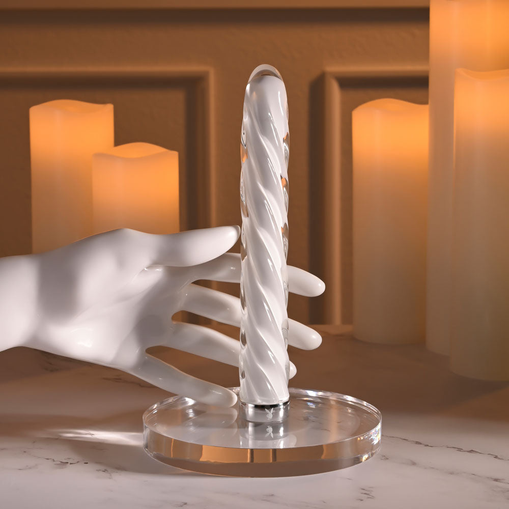 Playboy Pleasure IN A TWIST - Glass 17.5 cm USB Rechargeable Vibrator on display with candle background.