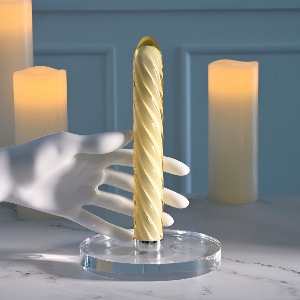 Playboy Pleasure TWIST OF FATE -  Glass 17.5 cm USB Rechargeable Vibrator resting on a display with soft candlelight.