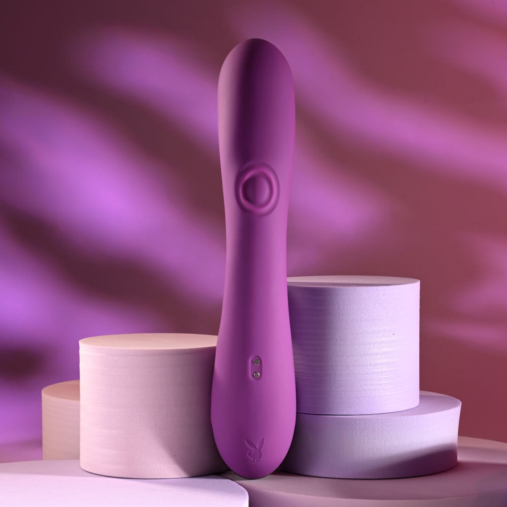 Playboy Pleasure BUSY BUNNY - 22.6 cm USB Rechargeable Rabbit Vibrator with Tapping Shaft on display with soft pastel background.