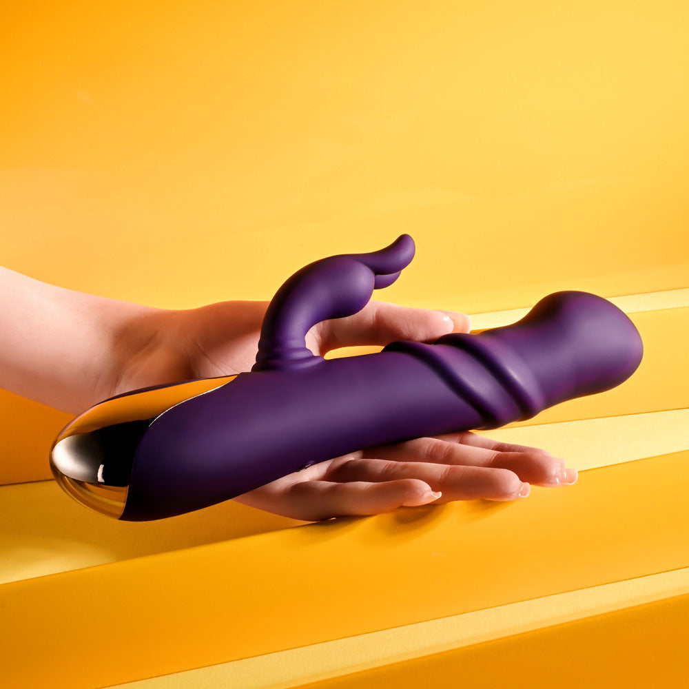Playboy Pleasure BUNNY PUNCH - 24.4 cm USB Rechargeable Twirling Rabbit Vibrator held in hand against yellow background.