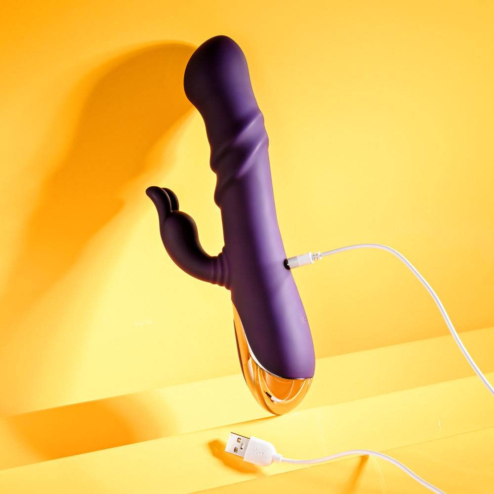 Playboy Pleasure BUNNY PUNCH - 24.4 cm USB Rechargeable Twirling Rabbit Vibrator charging against a bright yellow background.