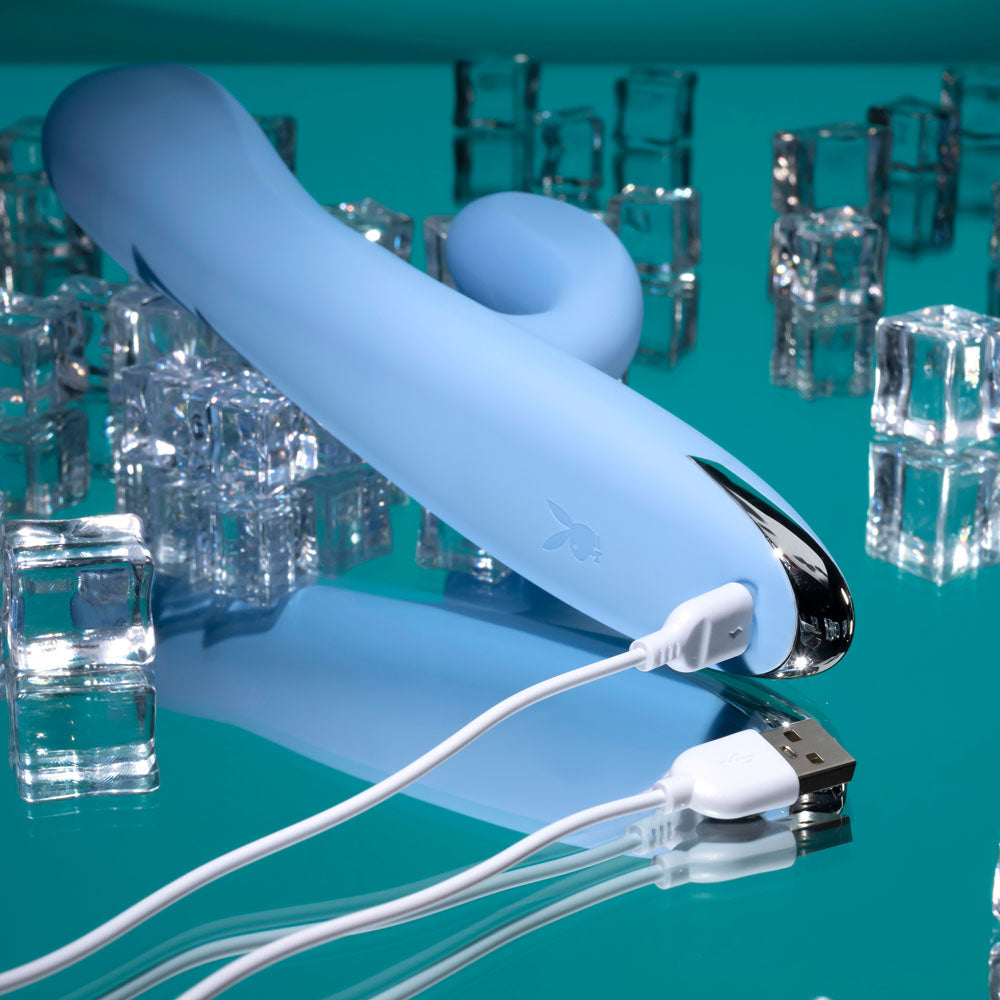 Playboy Pleasure UP AND AWAY - 26.7 cm USB Rechargeable Rabbit Vibrator on a reflective surface with ice cubes.