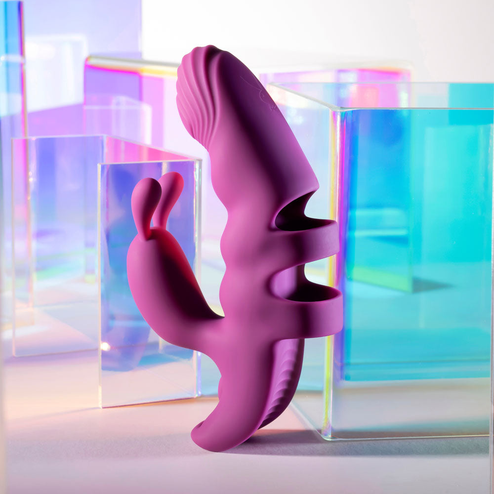Playboy Pleasure LEND A HAND - USB Rechargeable Finger Vibrator in vibrant purple against colorful geometric shapes.