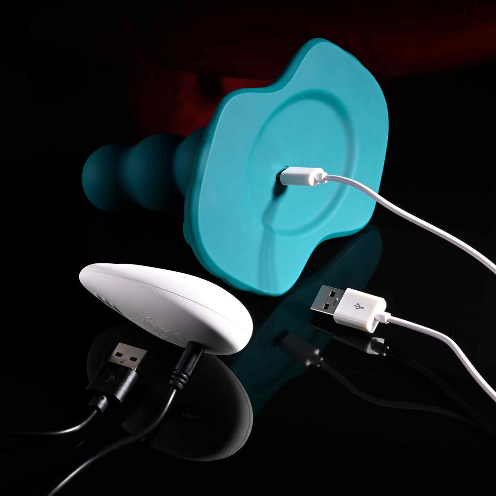 Playboy Pleasure HAVE A SEAT - USB Rechargeable Rideable Vibrator and Grinder Pad with Remote connected to charger.