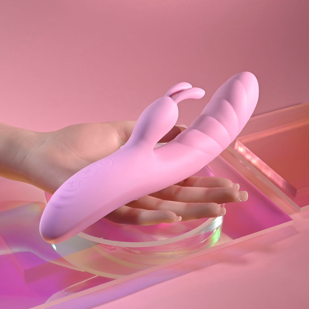 Playboy Pleasure RUB ME RIGHT -  23.2 cm USB Rechargeable Thrusting Rabbit Vibrator in hand on a colorful background.