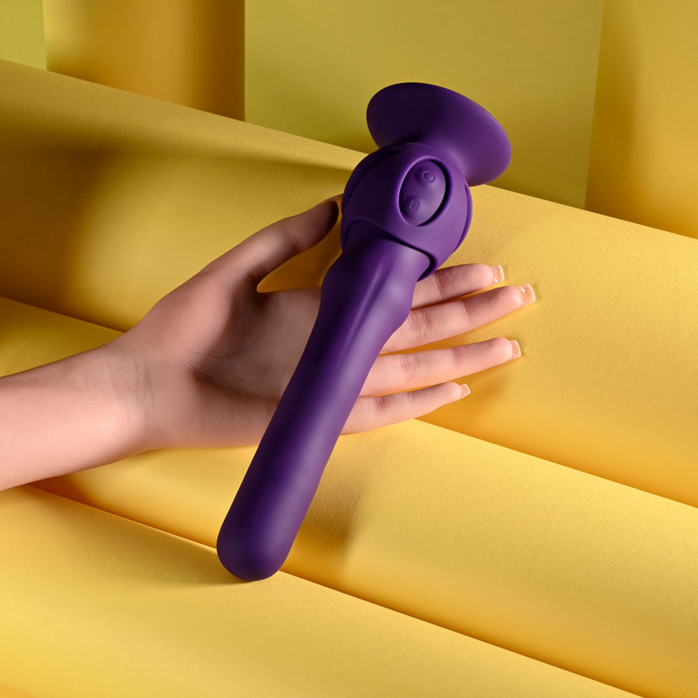 Playboy Pleasure WIGGLE IT - 23.9 cm USB Rechargeable Wiggling Vibrator in a hand against a yellow background.