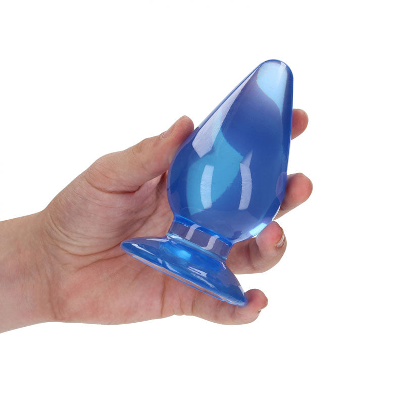 Hand holding a REALROCK 11.5 cm anal plug with a sleek, transparent design.