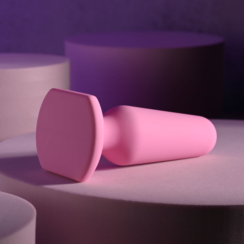 Selopa PETITE PLUG - 7.4 cm Butt Plug in pink silicone resting on soft pastel surfaces.