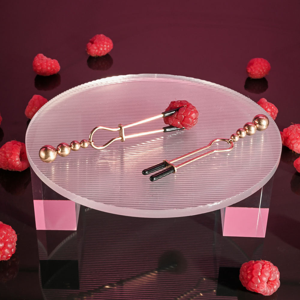 Selopa BEADED NIPPLE CLAMPS -  -  Nipple Clamps - Set of 2 displayed with raspberries on a clear plate.
