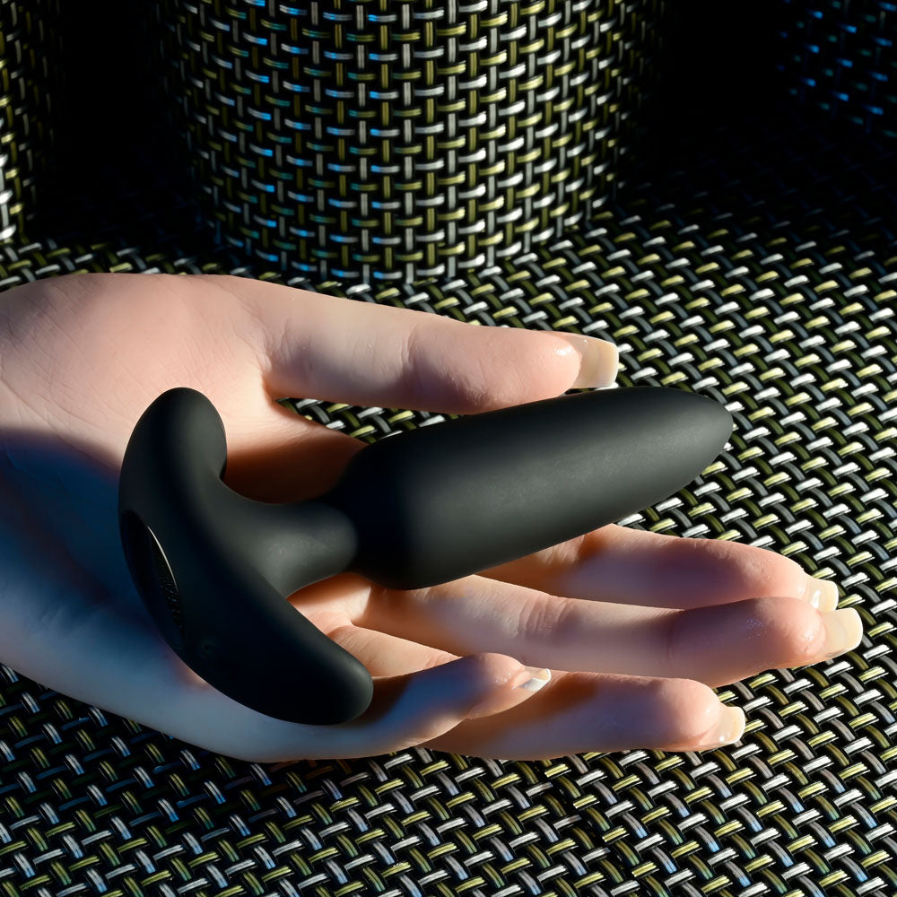 Selopa  BEAUTY -  11.3 cm USB Rechargeable Vibrating Butt Plug with Wireless Remote held in hand on textured background.